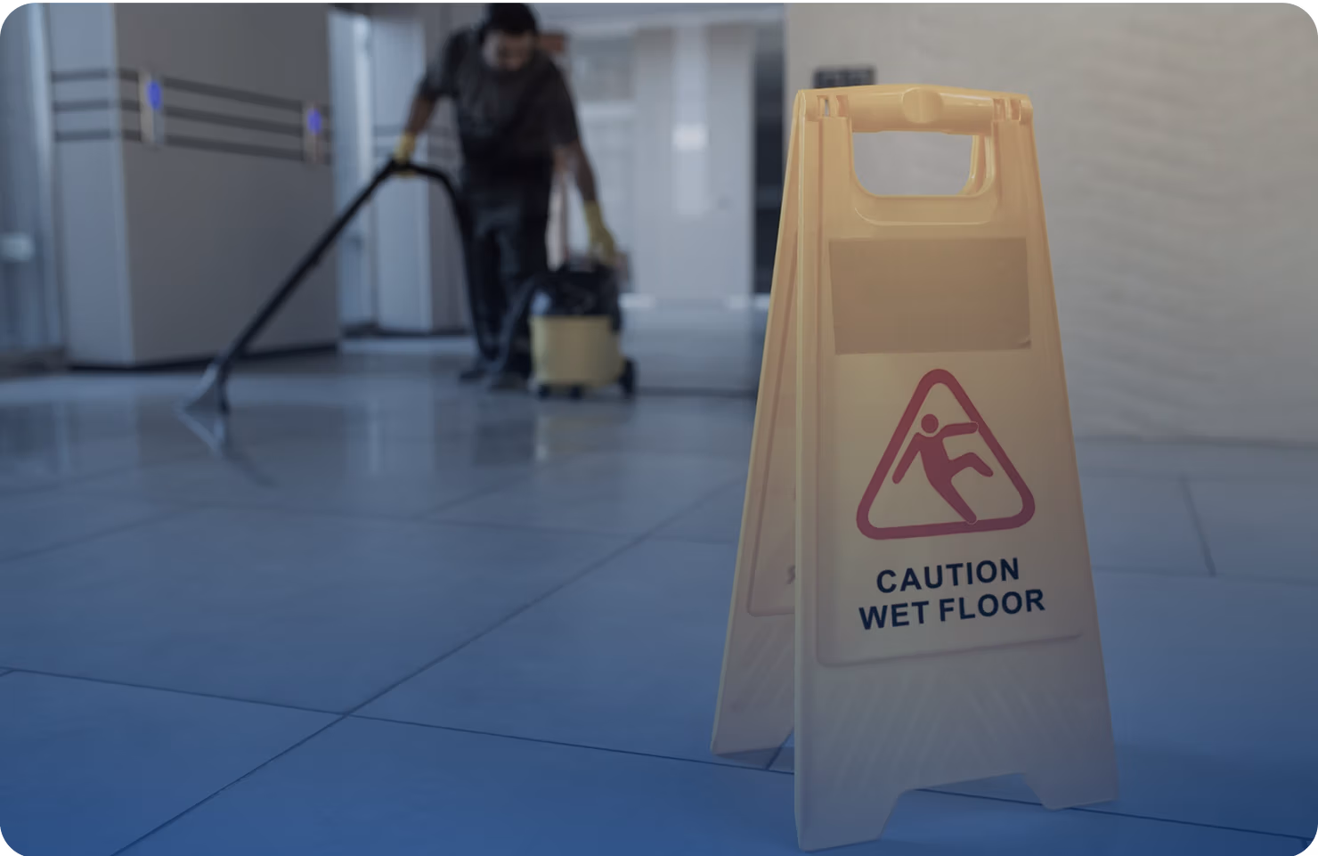Caution wet floor sign in a commercial setting with a worker cleaning the floor, emphasizing safety and prevention of slip and fall accidents.