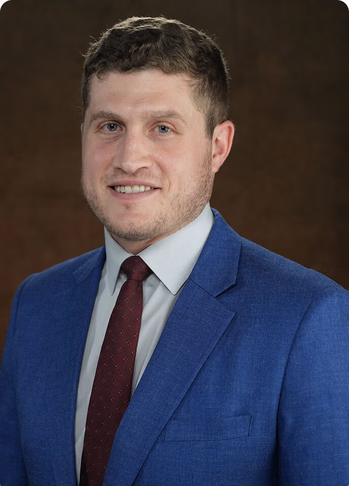 Ethen Ostroff, personal injury lawyer, smiling in a professional blue suit against a neutral background.
