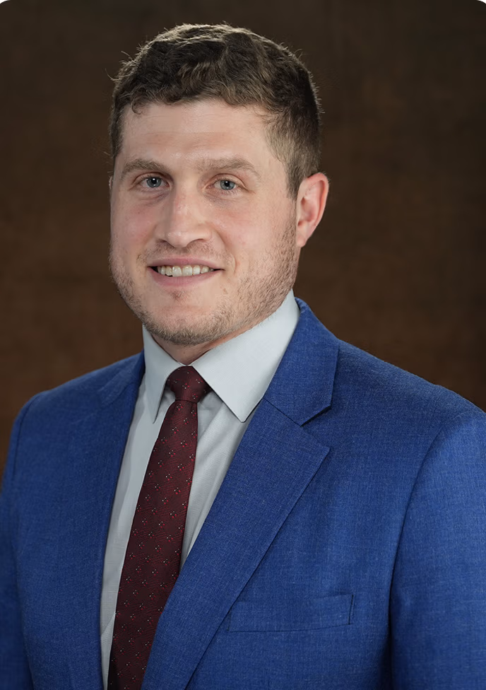 Ethen Ostroff, CEO of Ethen Ostroff Law, smiling in a blue suit, emphasizing personal and dedicated legal representation.