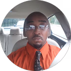 Professional man in an orange shirt and tie, wearing glasses, seated in a vehicle, representing Ethen Ostroff Law's commitment to personal injury legal representation.