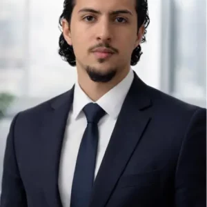 Ridky S., paralegal at Ethen Ostroff Law, wearing a dark suit and tie, standing confidently in a professional setting.